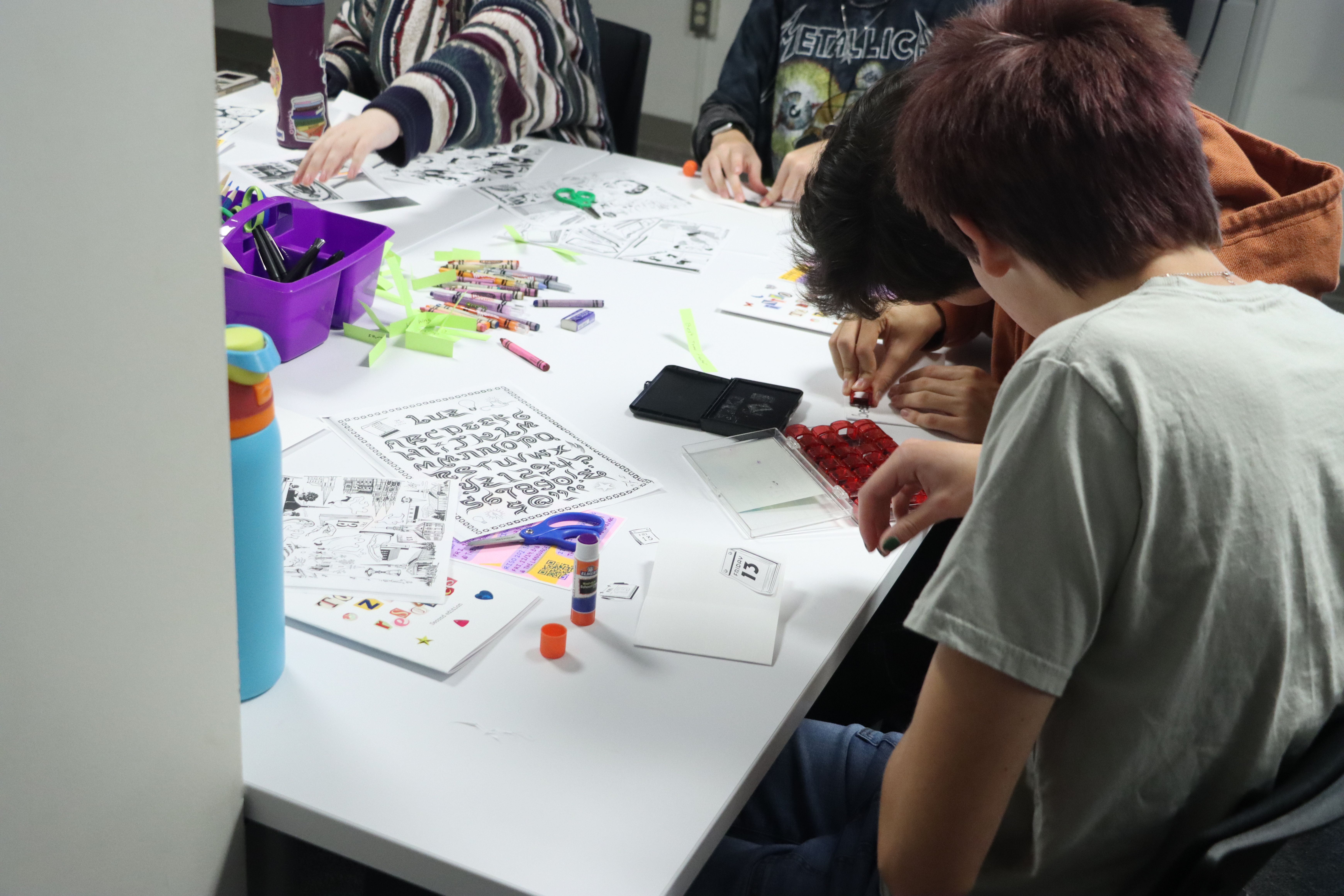 Students making zines with gluesticks and scissors